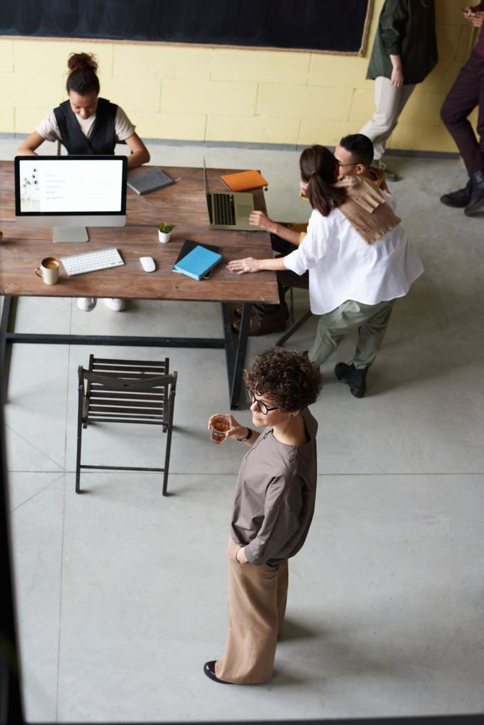 Services High angle view of a diverse team collaborating in an open office space with laptops and documents.