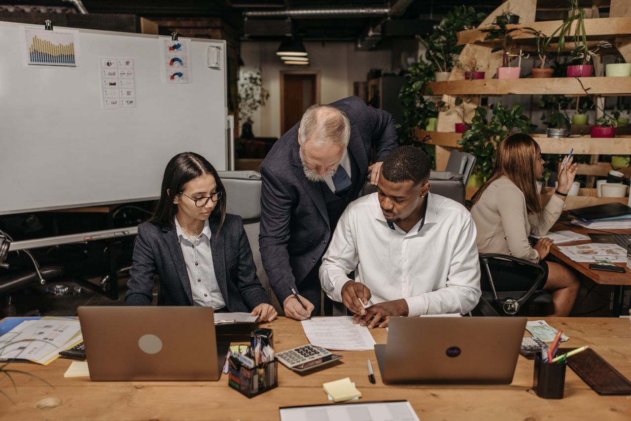 Services Business team working together with laptops in a collaborative office setting.